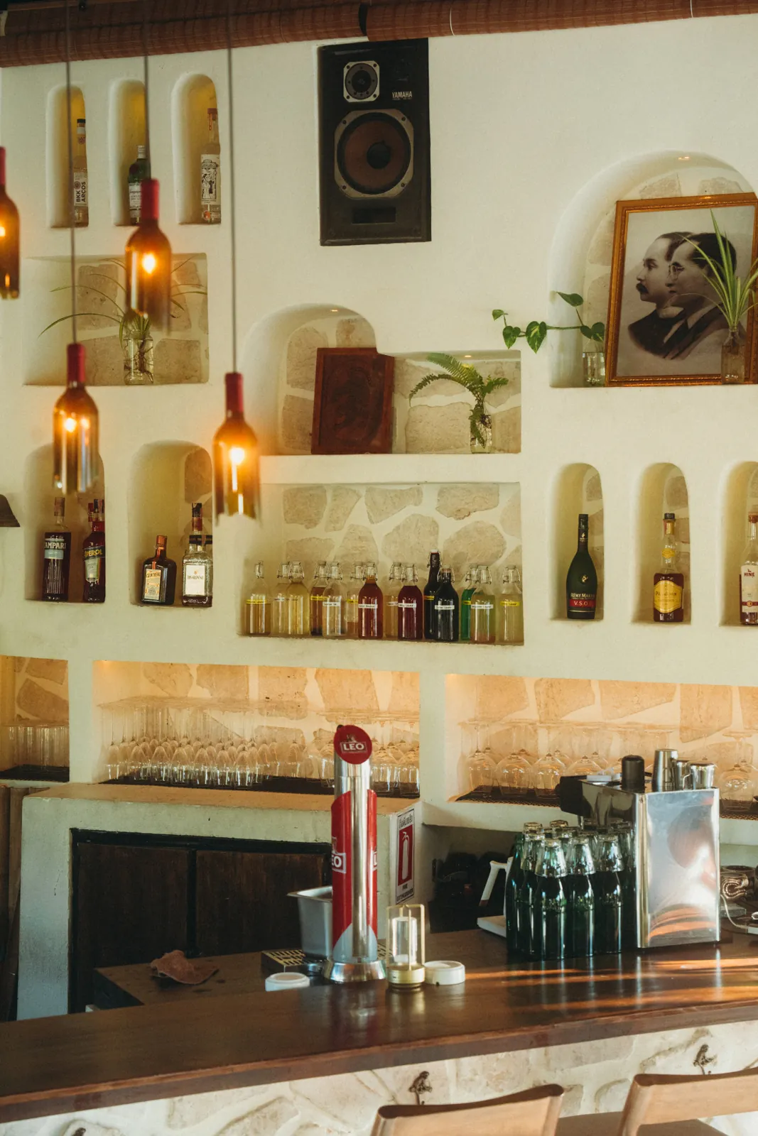 Arched bar niches with spirits, hanging bottle pendant lights and a vintage portrait at The Lakehouse